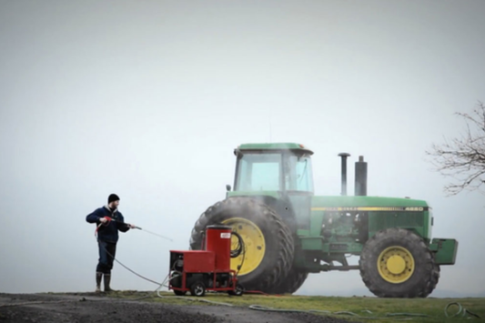 Hotsy cleaning a tractor out in a field