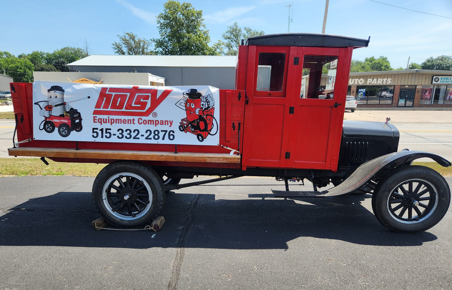 Vintage red truck with a Hotsy Equipment Company sign on a clear day.
