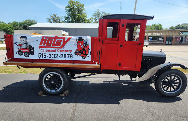 Vintage red truck with a Hotsy Equipment Company sign on a clear day.